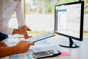 duas pessoas em frente a um computador fazendo gestao de fluxo de caixa com o auxilio de um ERP